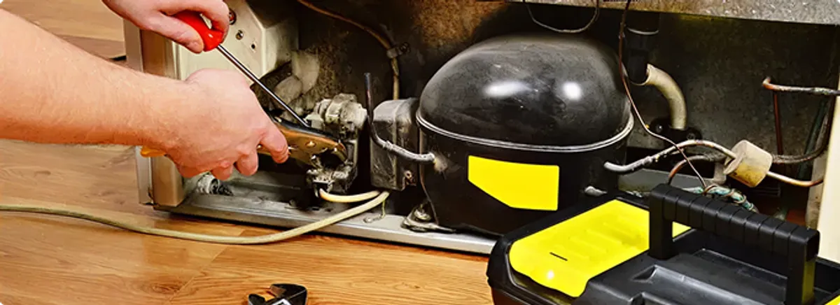 Refrigerator repair technician fixing the compressor and wiring in Dracut, MA